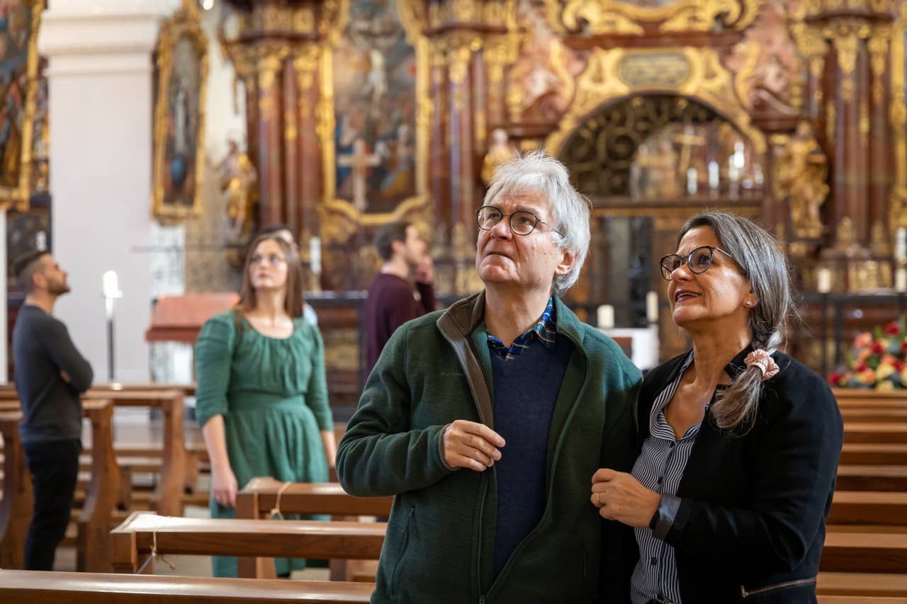Ein Ehepaar steht in der Klosterkirche, sie blicken nach oben. Im Hintergrund stehen weitere Personen