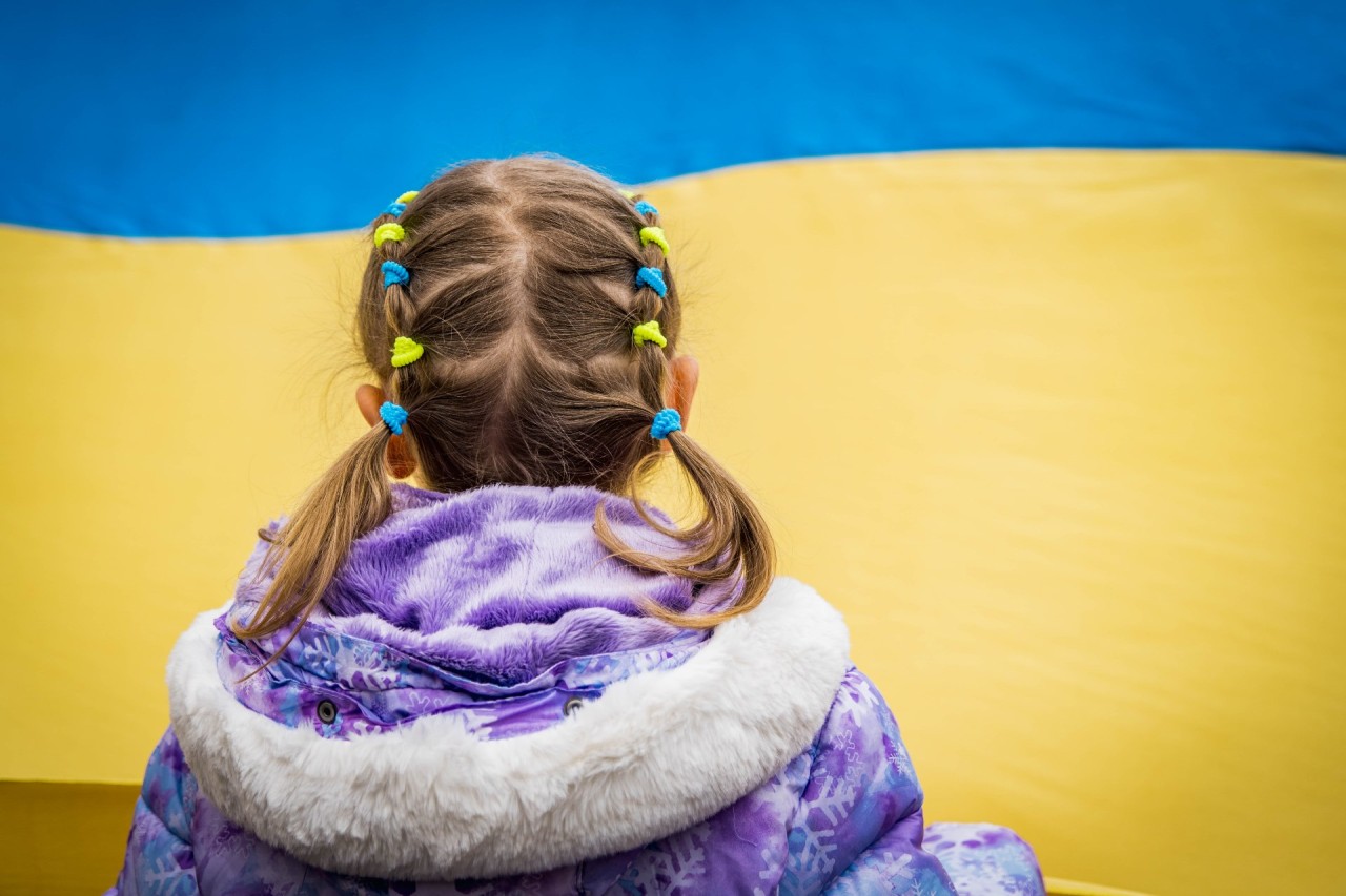 Mädchen schaut ukrainische Flagge an