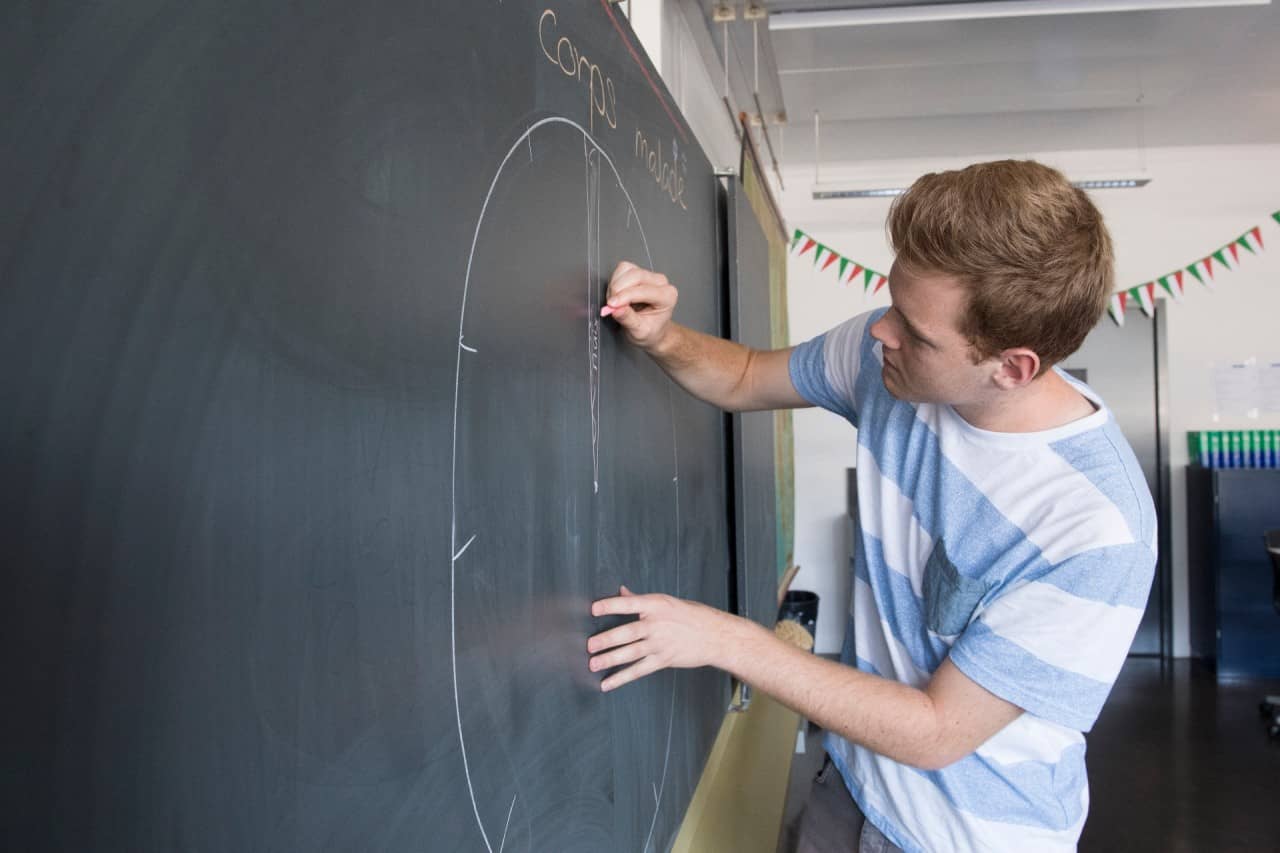 Schüler zeichnet eine Uhr auf die Wandtafel