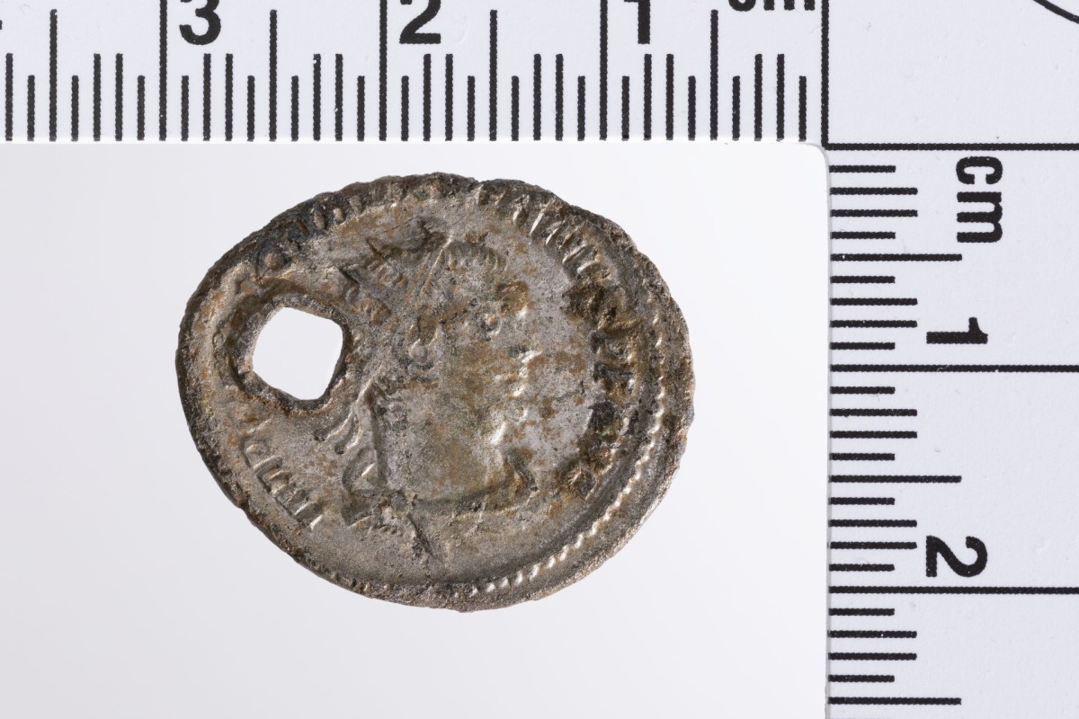 Silberne Münze mit fein geprägtem Kaiserporträt und links davon ein Loch.