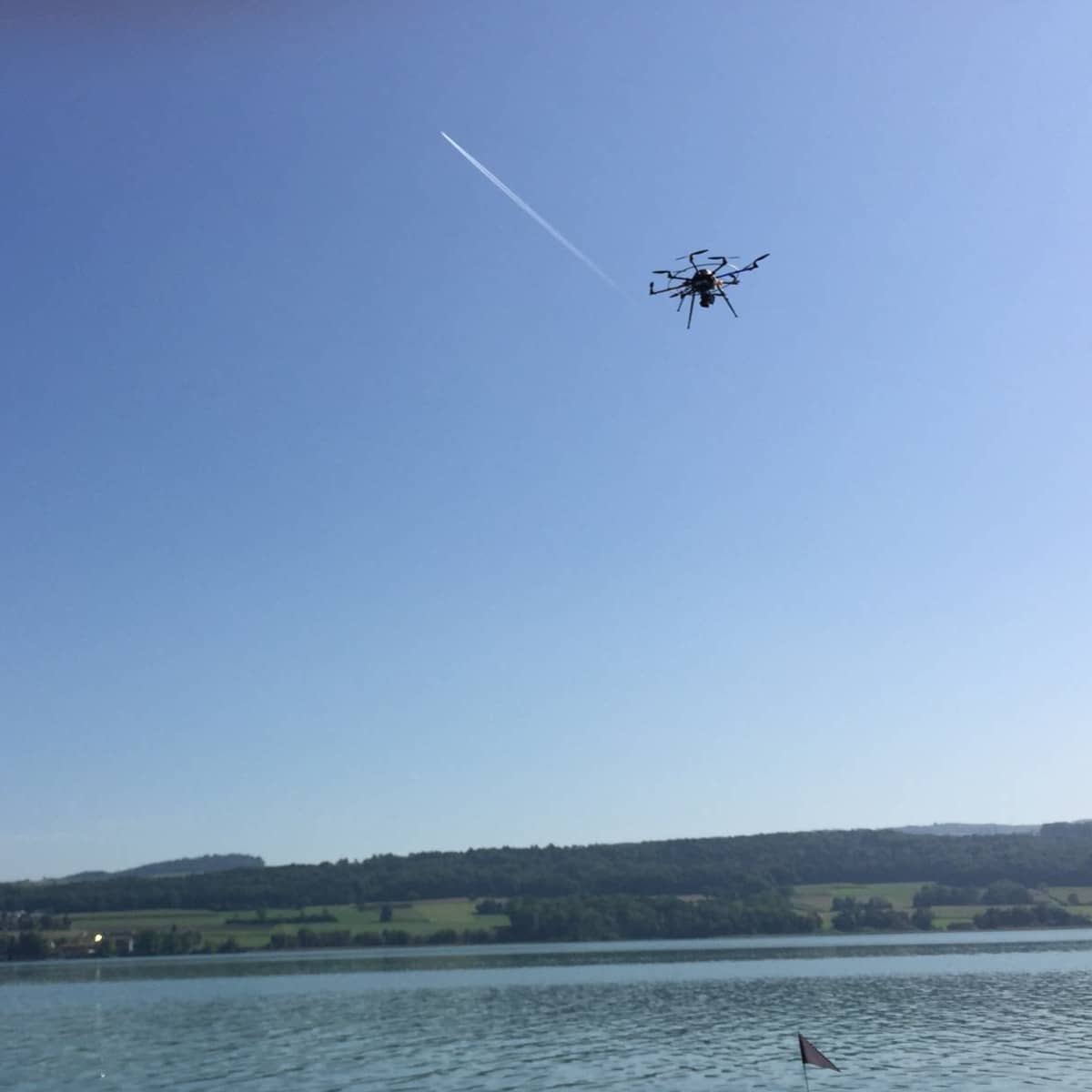 Drohne fliegt über Taucher im Wasser.