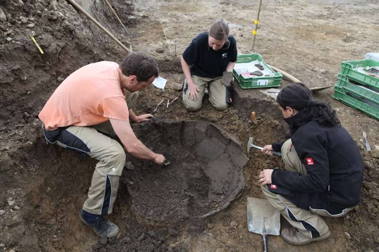 Archäologen graben das Vorratsgefäss aus.