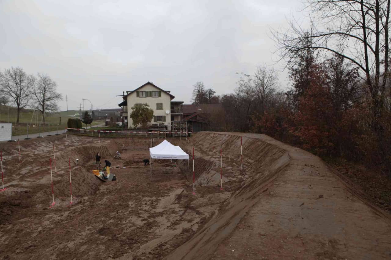 Archäologen und ein weisses Grabungszelt auf der Baustelle.