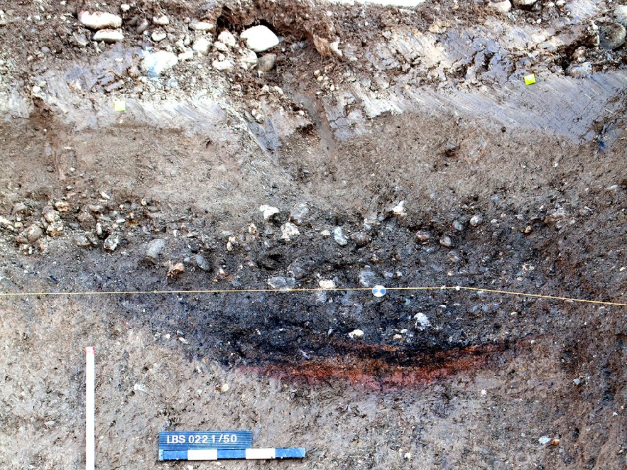 Blick auf ein archäologisches Profil mit verschiedenen Schichten in unterschiedlichen Brauntönen.