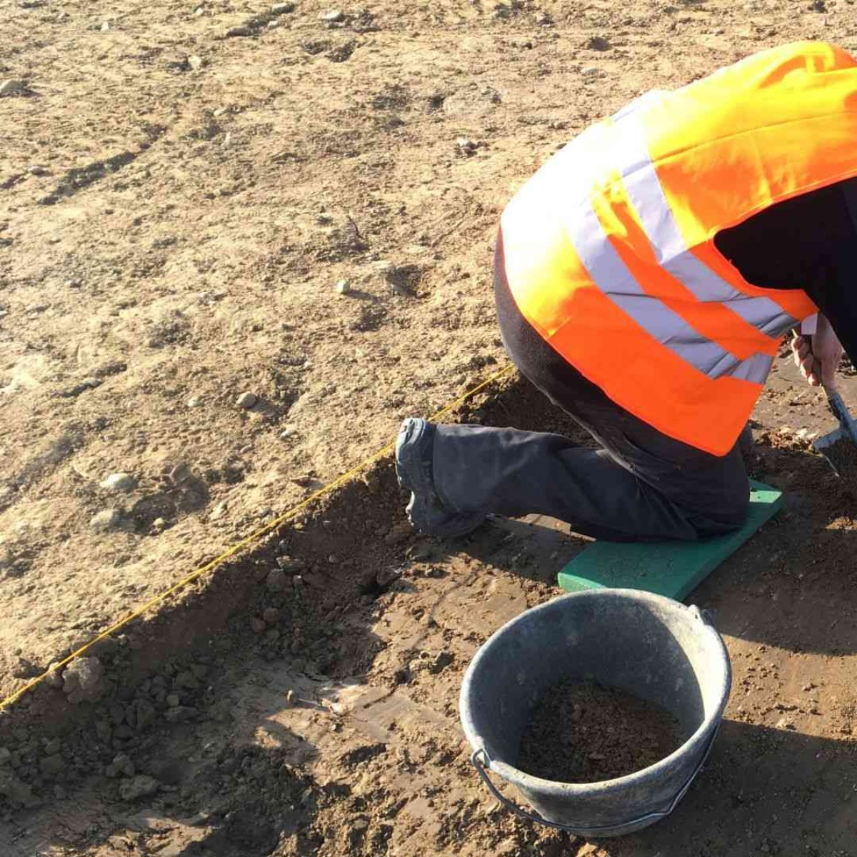 Ausgräber mit Spitzkelle am Freilegen von Strukturen.
