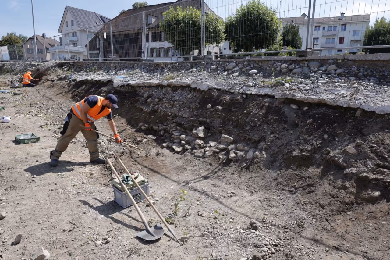 Ausgräber präpariert eine Fläche mit dem Langstielkratzer. Im Hintergrund die Zürcherstrasse.