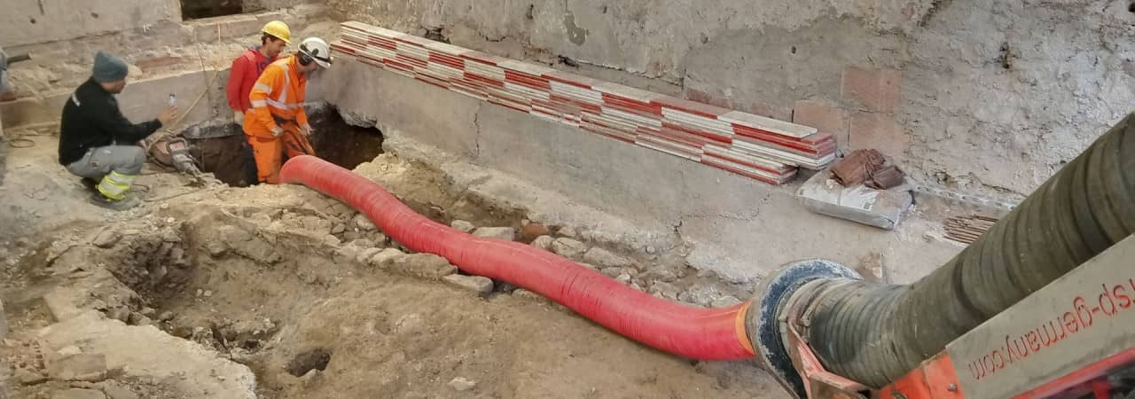 Mit dem Saugbagger graben drei Grabungsmitarbeiter im Keller des Hörnli.
