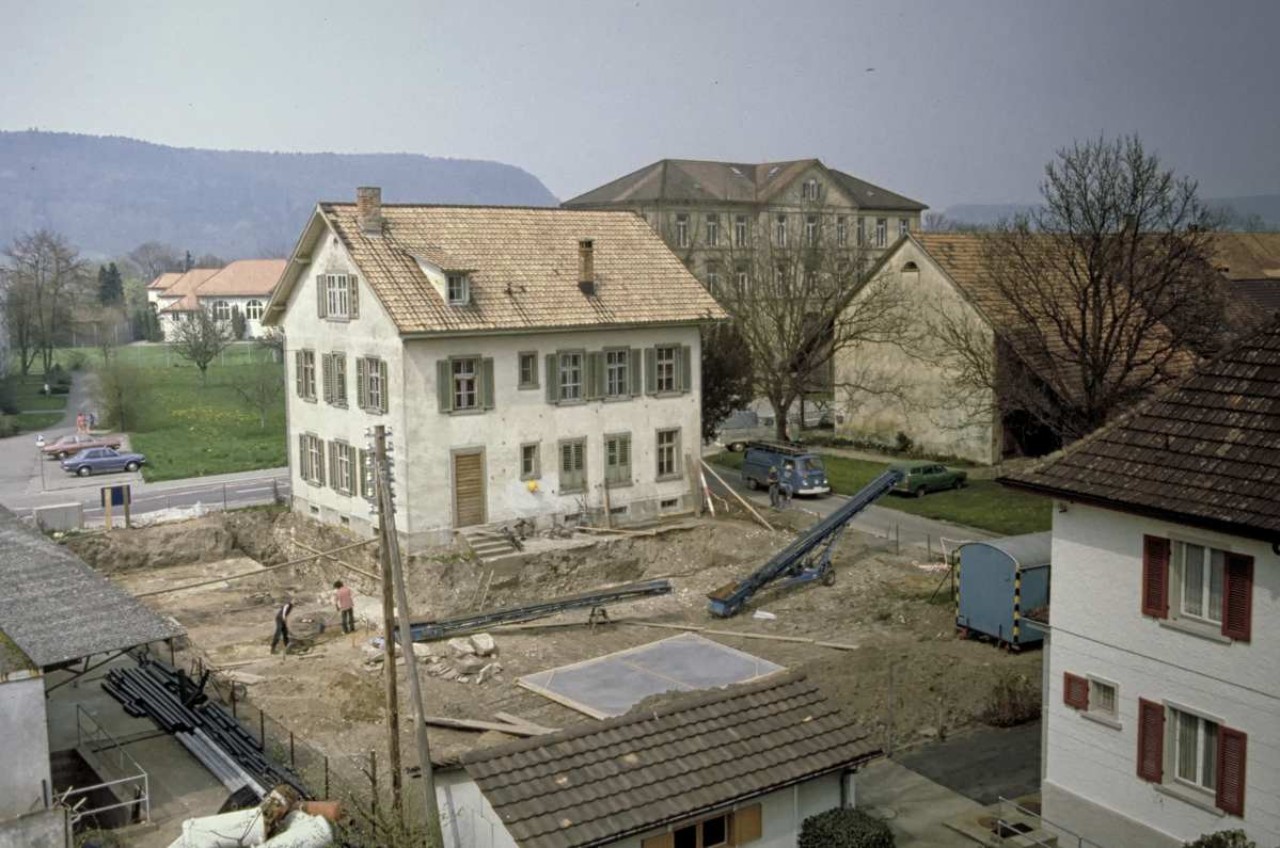 Ausgrabung mit Wohnhaus dahinter.