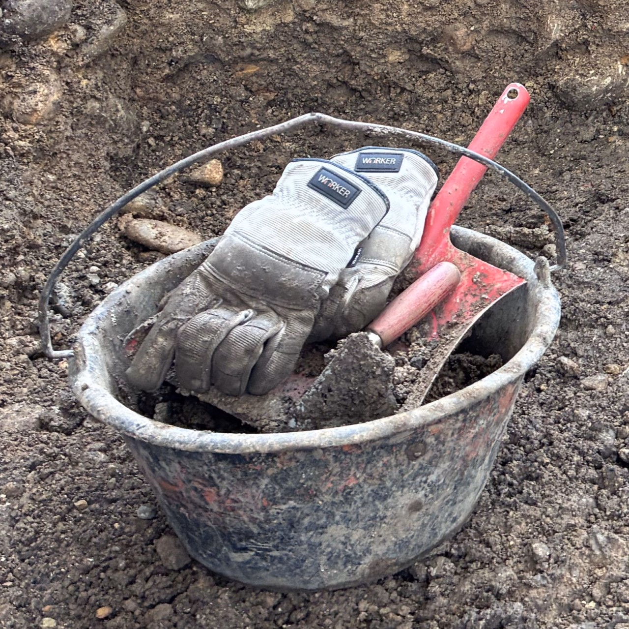 Kessel mit Kehrblech, Spitzkelle und Handschuhen darin.