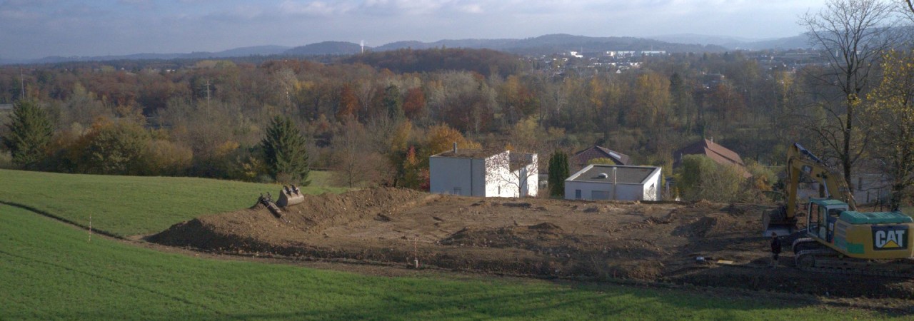 Blick von Weitem auf die Ausgrabungsstelle, mit blauem Himmel und Weitsicht über das Aaretal. 