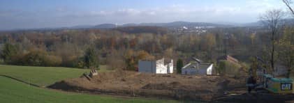 Blick von Weitem auf die Ausgrabungsstelle, mit blauem Himmel und Weitsicht über das Aaretal. 