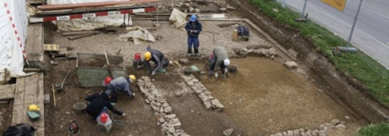 Ein Grabungsteam von 5 Leuten ist an der Arbeit inmitten von römischen Mauern.