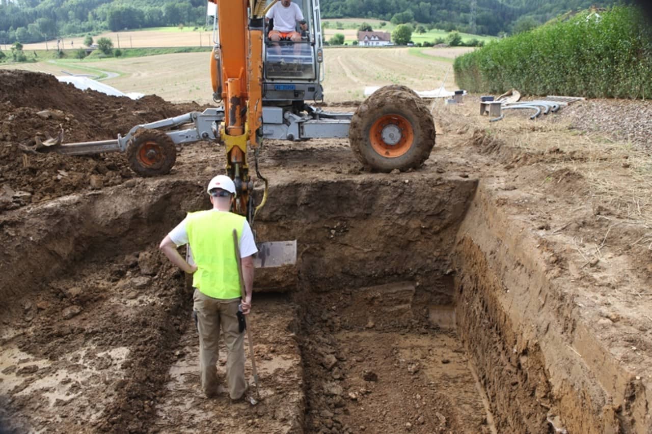 Archäologe begutachtget eine Baggergrube. 
