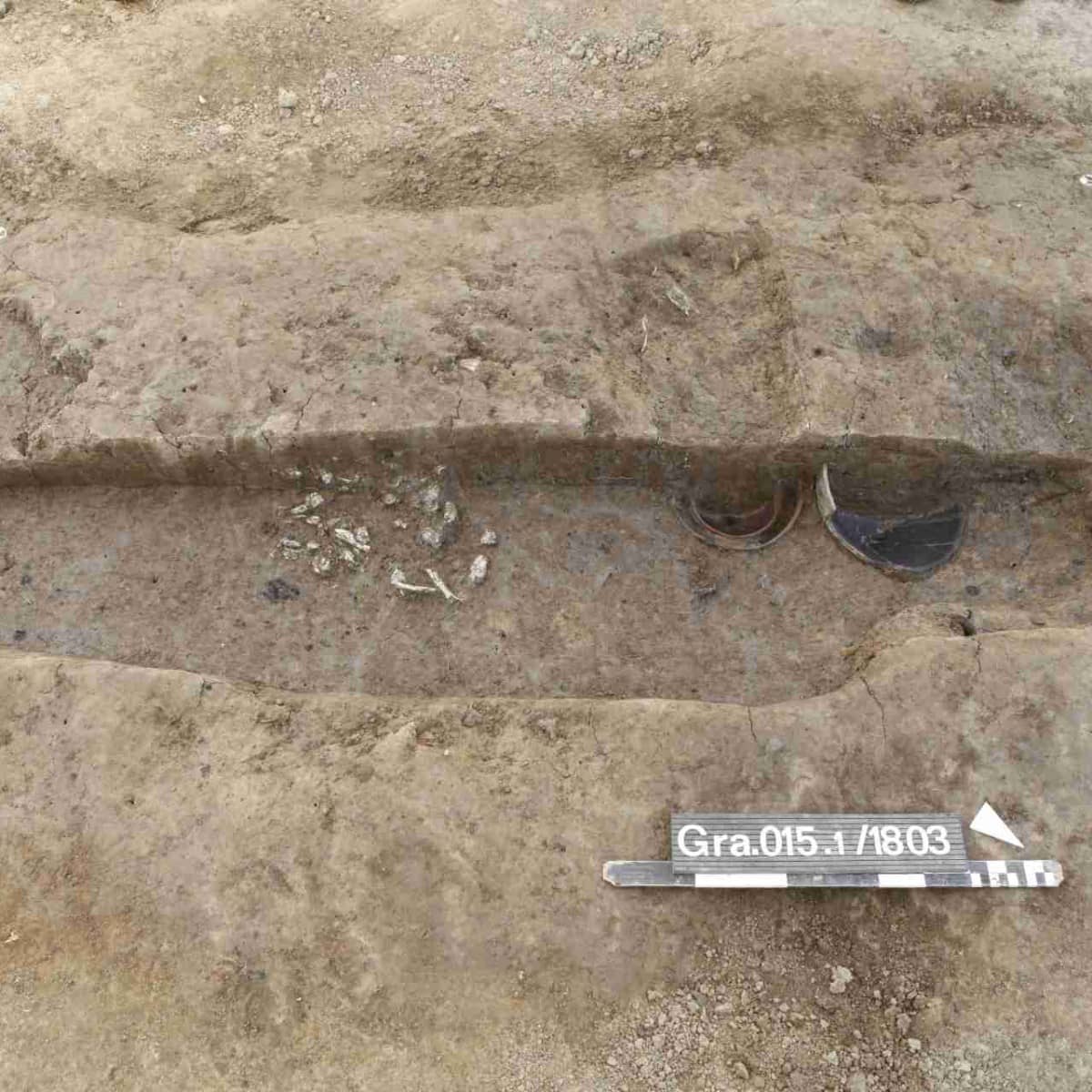 Freigelegte Grabgrube mit Knochen und Beigabengefässen.