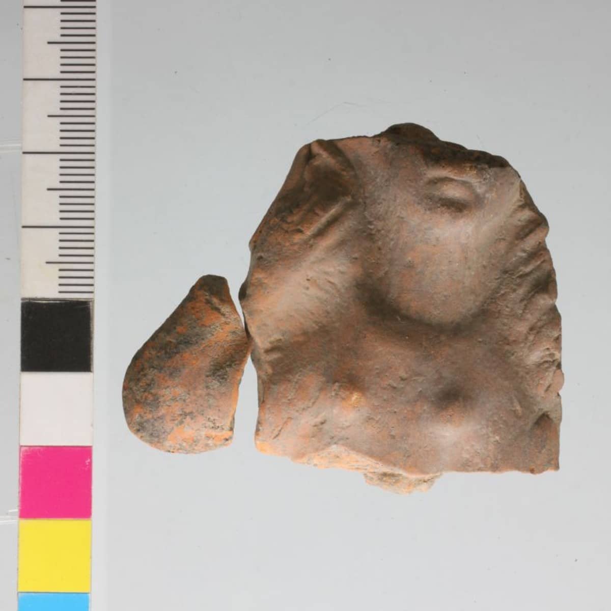  	Fragment einer hier produzierten Venusstatuette aus lokalem, orangefarbenen Ton. 