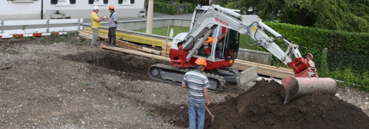 Ein Bagger macht den Erdabtrag und ein Archäologe überwacht diese Arbeiten.