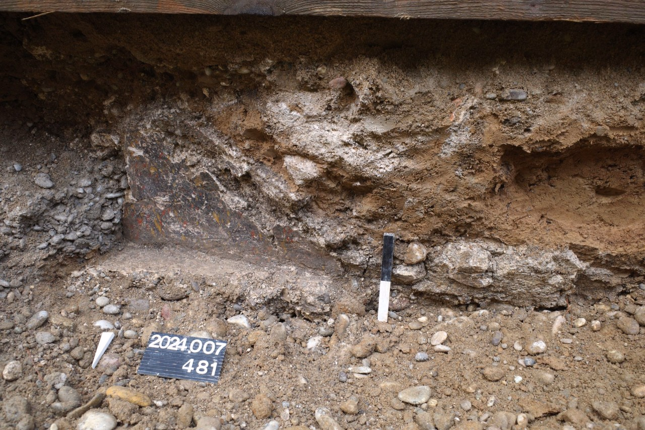 Freigelegte Mauerecke eines Gebäudes mit bemalten Wandverputz.