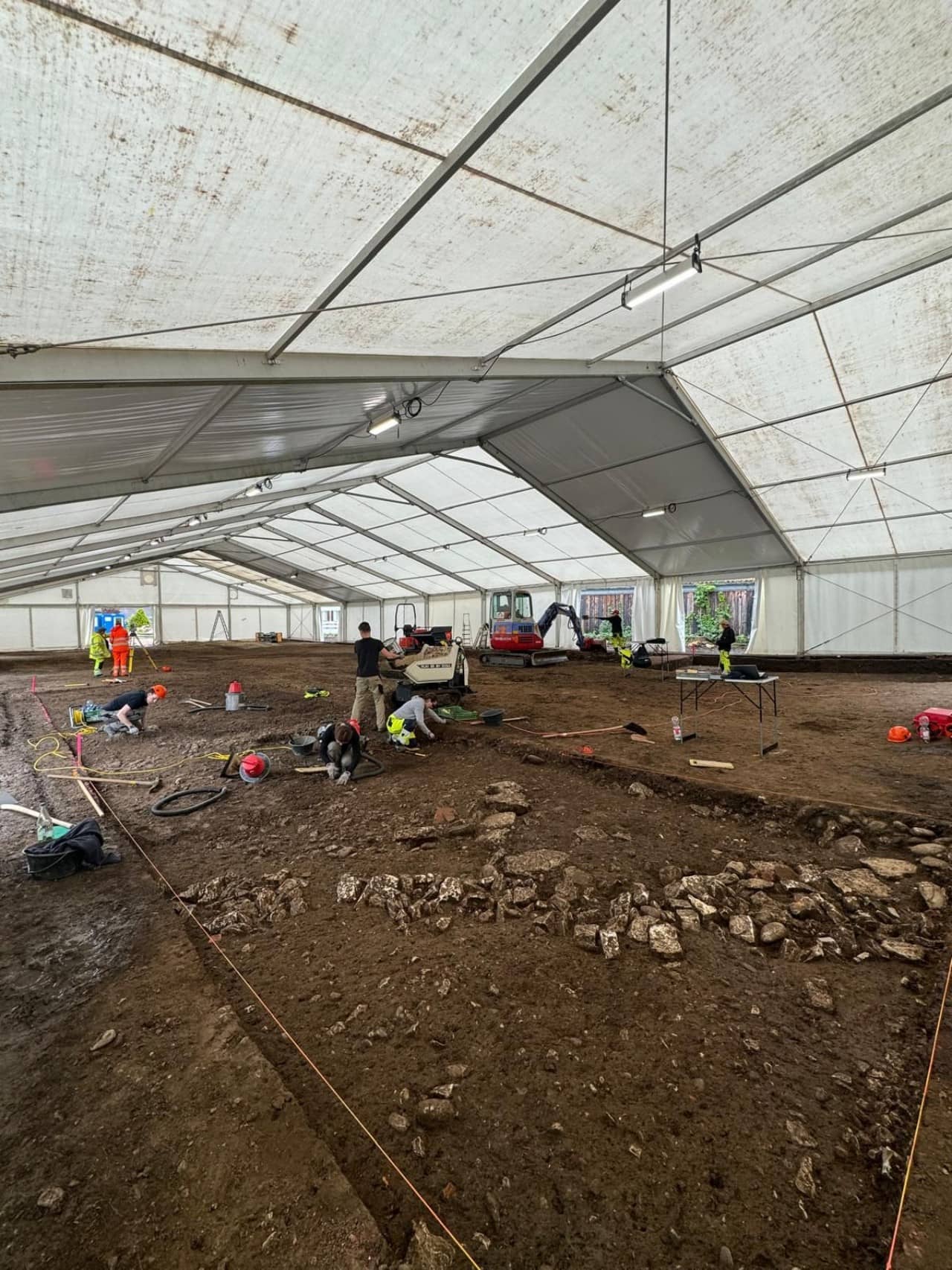 Blick ins Grabungszelt mit Ausgrabungsmitarbeitenden bei der Arbeit.