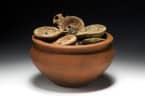 Eine römische Kochschüssel randvoll gefüllt mit Lampen und Münzen.