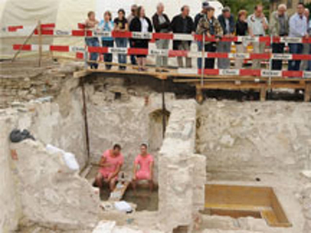 Zwei "Badegäste" beim Fussbad in römischer Therme vor interessierten Zuschauern.