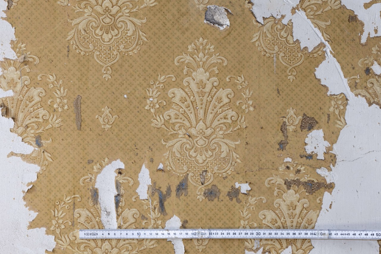 Gelb gemusterte Tapate mit floralen wappenartigen Motiven.