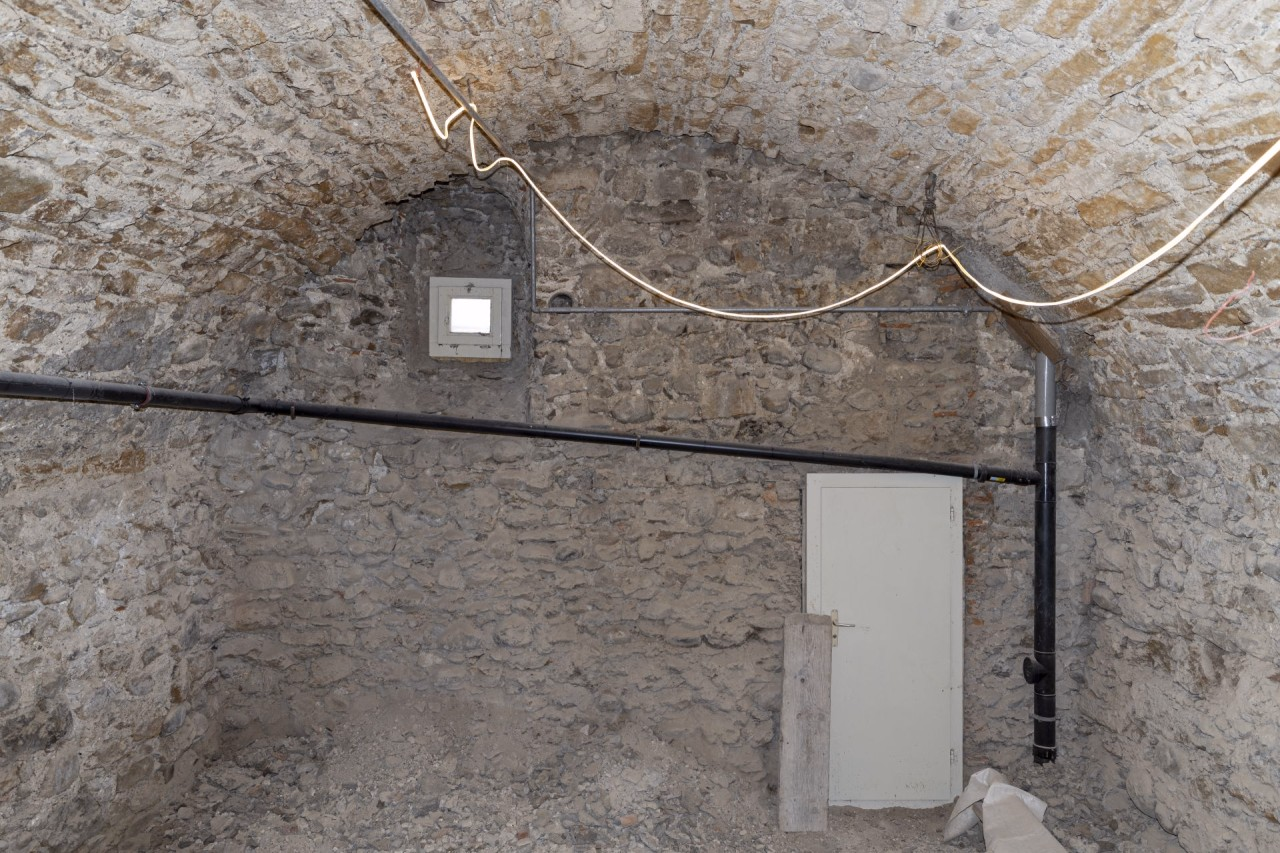 Gewölbekeller mit halbrunder Decke, hintenb rechts eine Tür und hinten links oben ein Fenster.