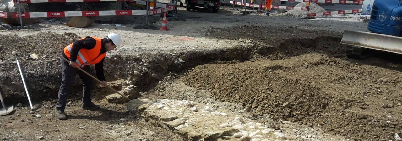 Grabungsarbeiter legt Mauerfundamente frei.