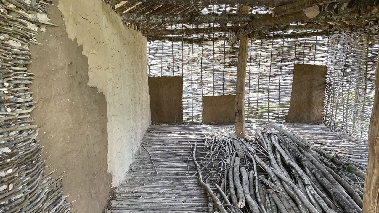 Blick ins Innere des Pfahlbauhauses mit teils mit Lehm verputzten Flechtwerkwänden.
