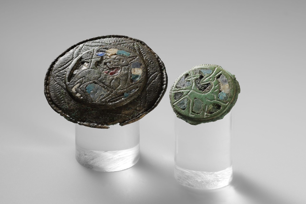 Zwei Scheibenfibeln mit Darstellungen eines Lamms.