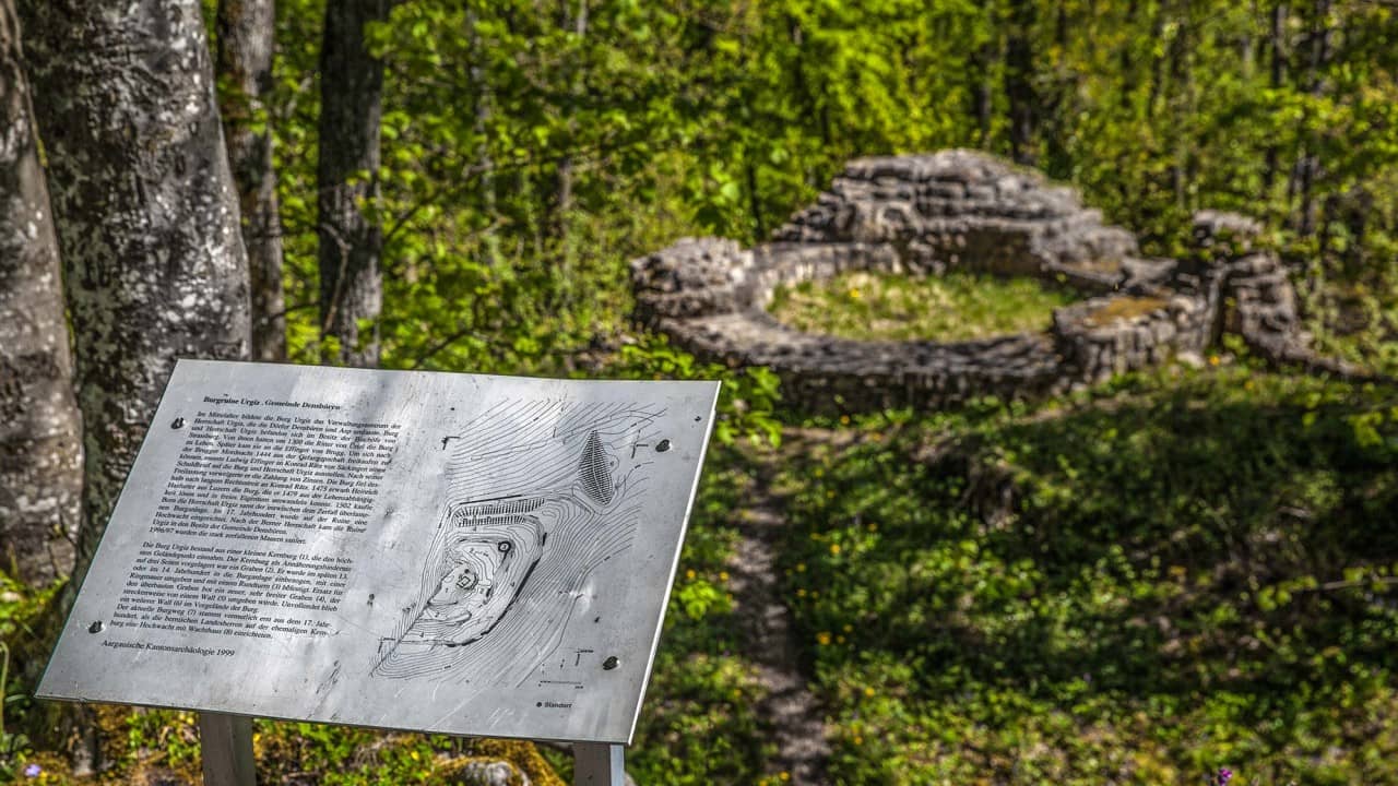 Im Vordergrund Infotafel, im Hintergrund die Ruinen der Burg Urgiz