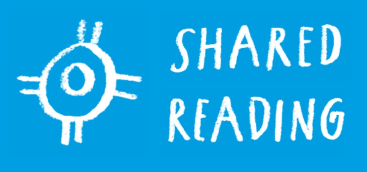 Weisses Symbol mit einem Kreis und Strahlen auf blauem Hintergrund, daneben der Schriftzug "Shared Reading".