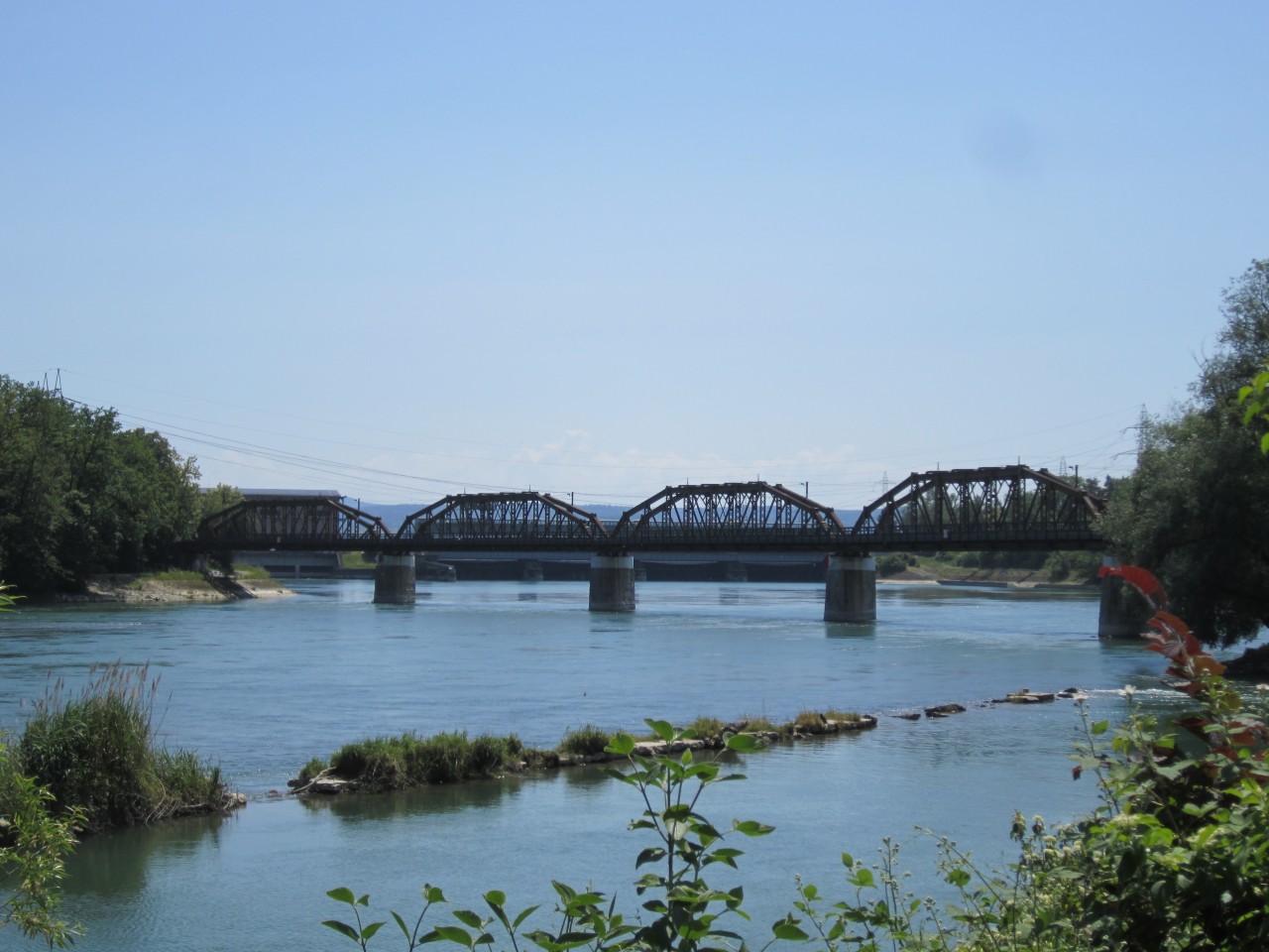Farbfoto einer Brücke mit Bögen über einen Fluss.
