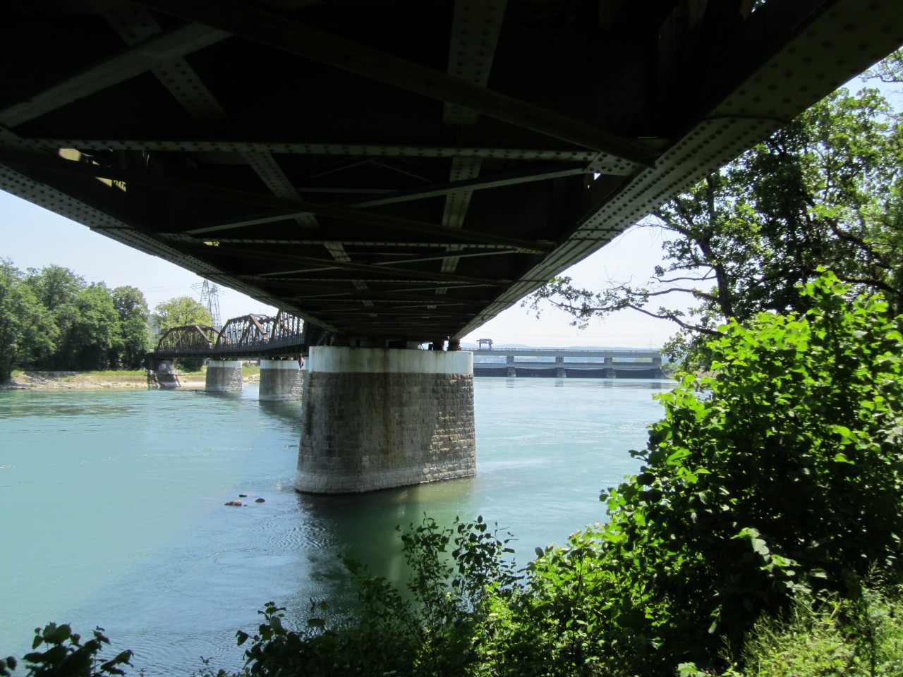 Farbfoto einer Brücke. Unter der Brücke mit Blick aufs andere Ufer.