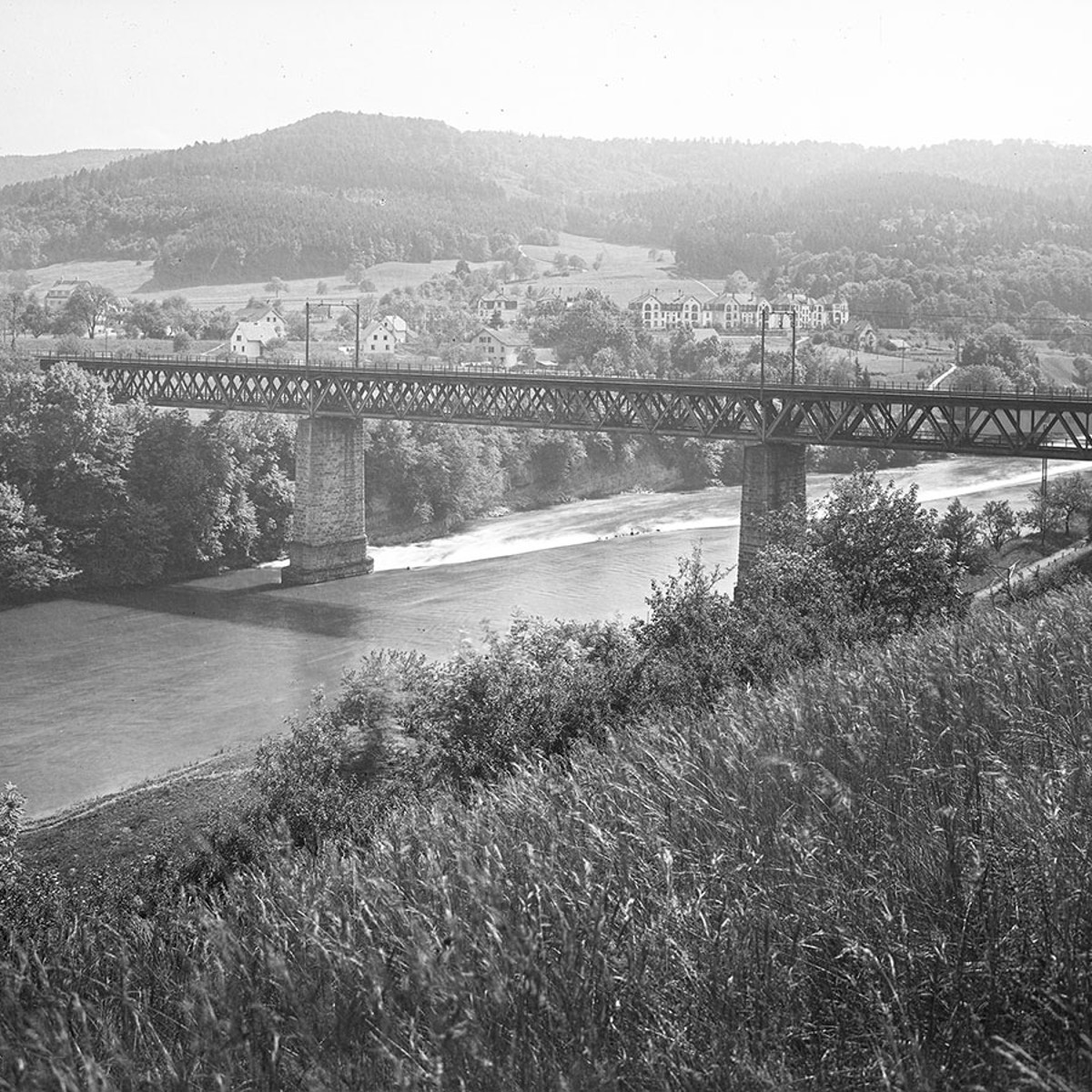 Eine Schwarzweissfotografie aus der Vogelperspektive mit Blick auf die Bahnbrücke, die über die Limmat spannt.