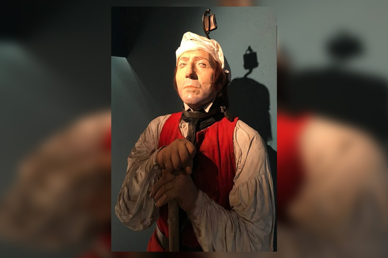 Figur eines Gefangenen mit Eisenring mit einer Schelle um den Hals.