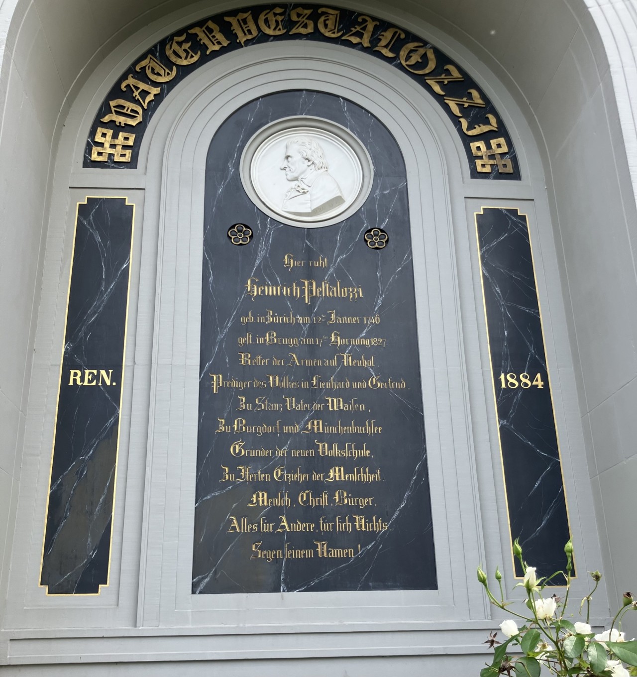 Gedenktafel mit goldener Schrift auf schwarzem Marmor und einem gemeisselten Porträt von Pestalozzi.