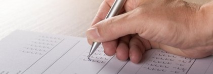 Eine Hand mit Kugelschreiber, die einen Fragebogen ausfüllt.