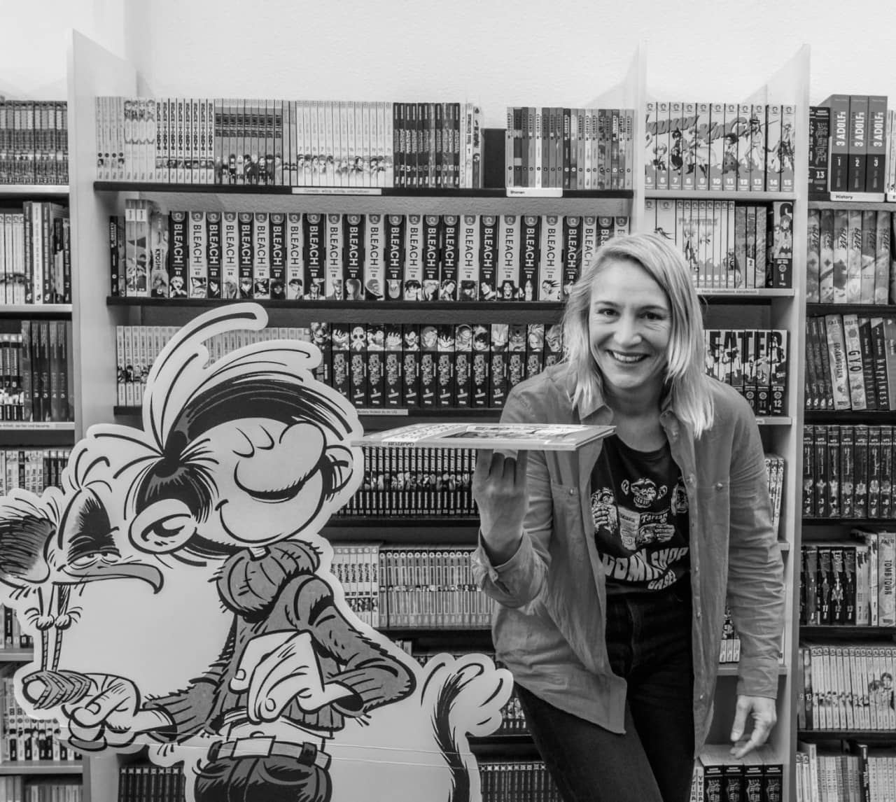 Schwarz-weiss Portät von Angela Heimberg vor Bücherregalen stehend.