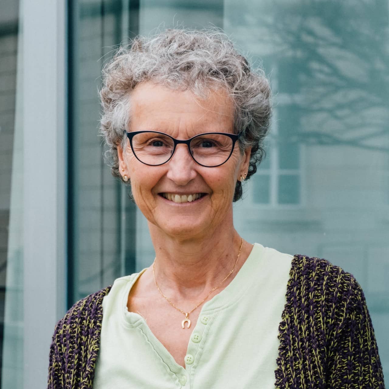 Yvonne Linder steht vor der Fassade der Kantonsbibliothek und lächelt freundlich in die Kamera.