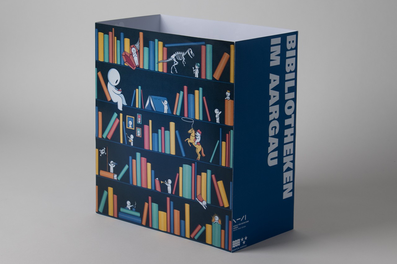 Die Maquette der Tasche aus Papier zeigt den Entwurf "Die Verspielte". Darauf zu sehen ist ein buntes Bücherregal. Im Regal und zwischen den Büchern turnen, sitzen und bewegen sich Figuren in weisser Farbe.