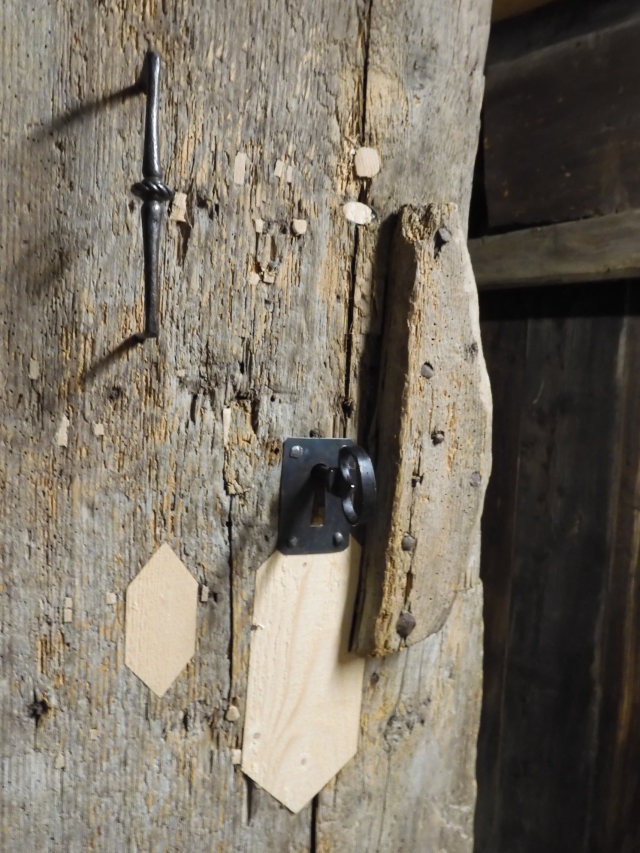 Detailansicht der restaurierten Türe mit einzelnen Flickstellen mit neuem Holz und restauriertem Schloss. 
