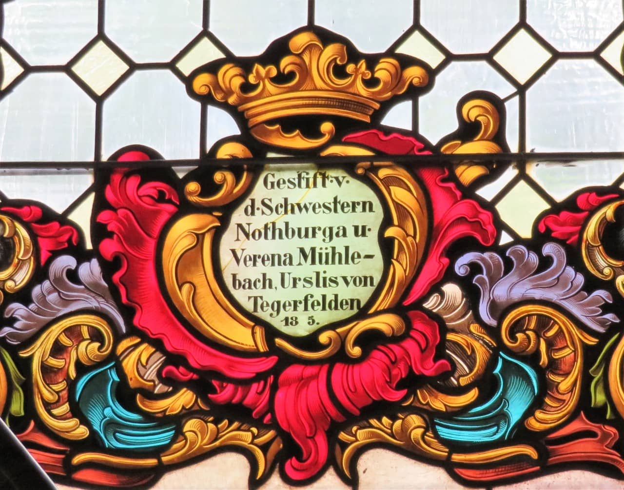Fenster beim linken Seitenaltar. Detail mit der Inschrift, welche die Schwestern Mühlebach aus Tegerfelden als Stifterinnen ausweist.