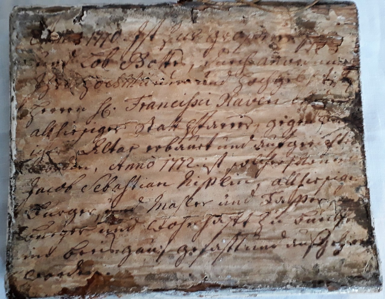 Rückseite des Holztäfelchens mit dicht beschriebenem Papierblatt.