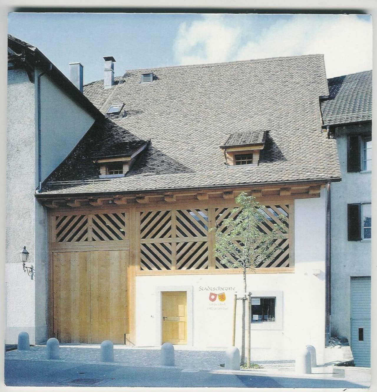 Aussenansicht der Stadtscheune mit Holzfassade. Davor ein junger Baum.