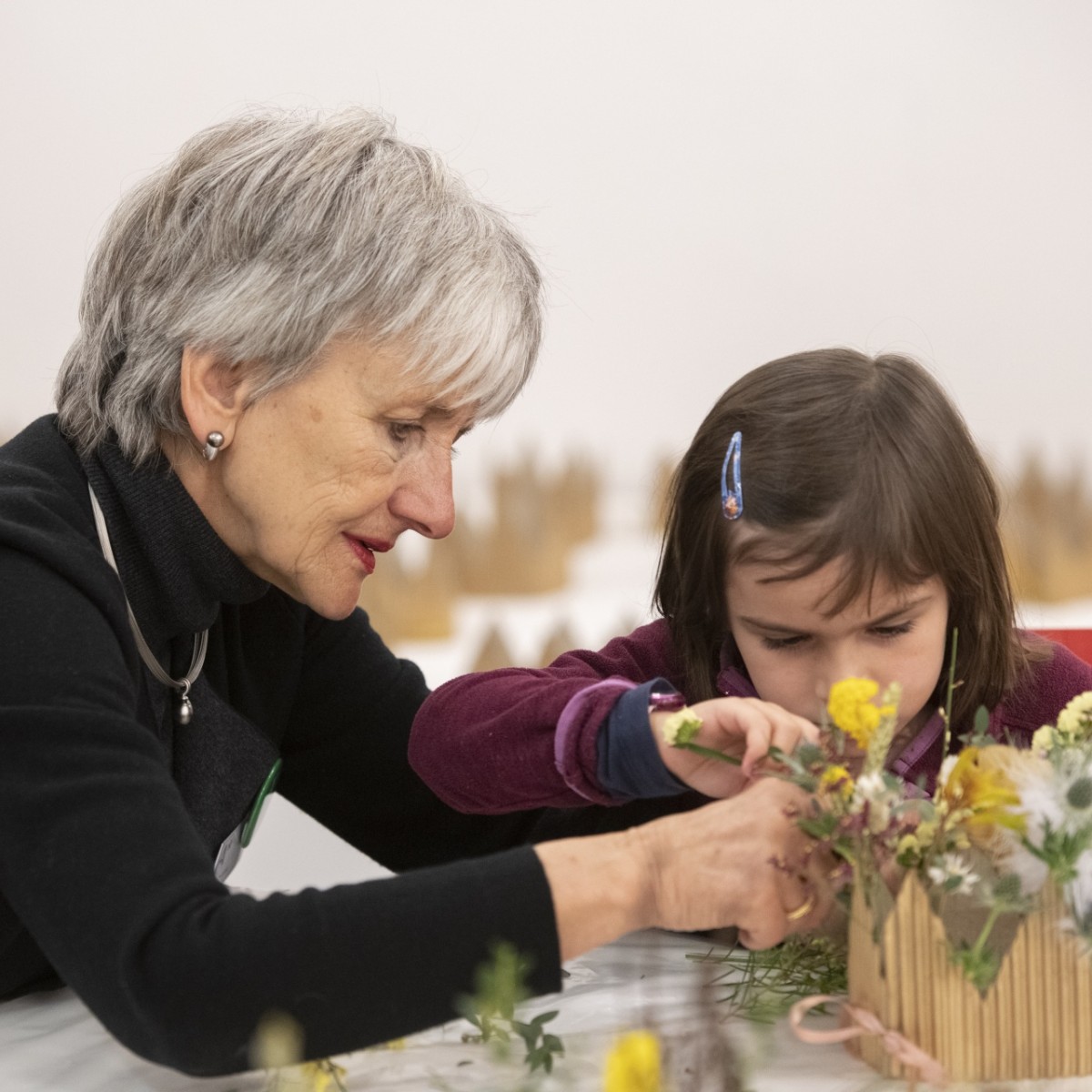 Eine Freiwillige zusammen mit einem Kind im Kunstworkshop am Blumenstecken. 