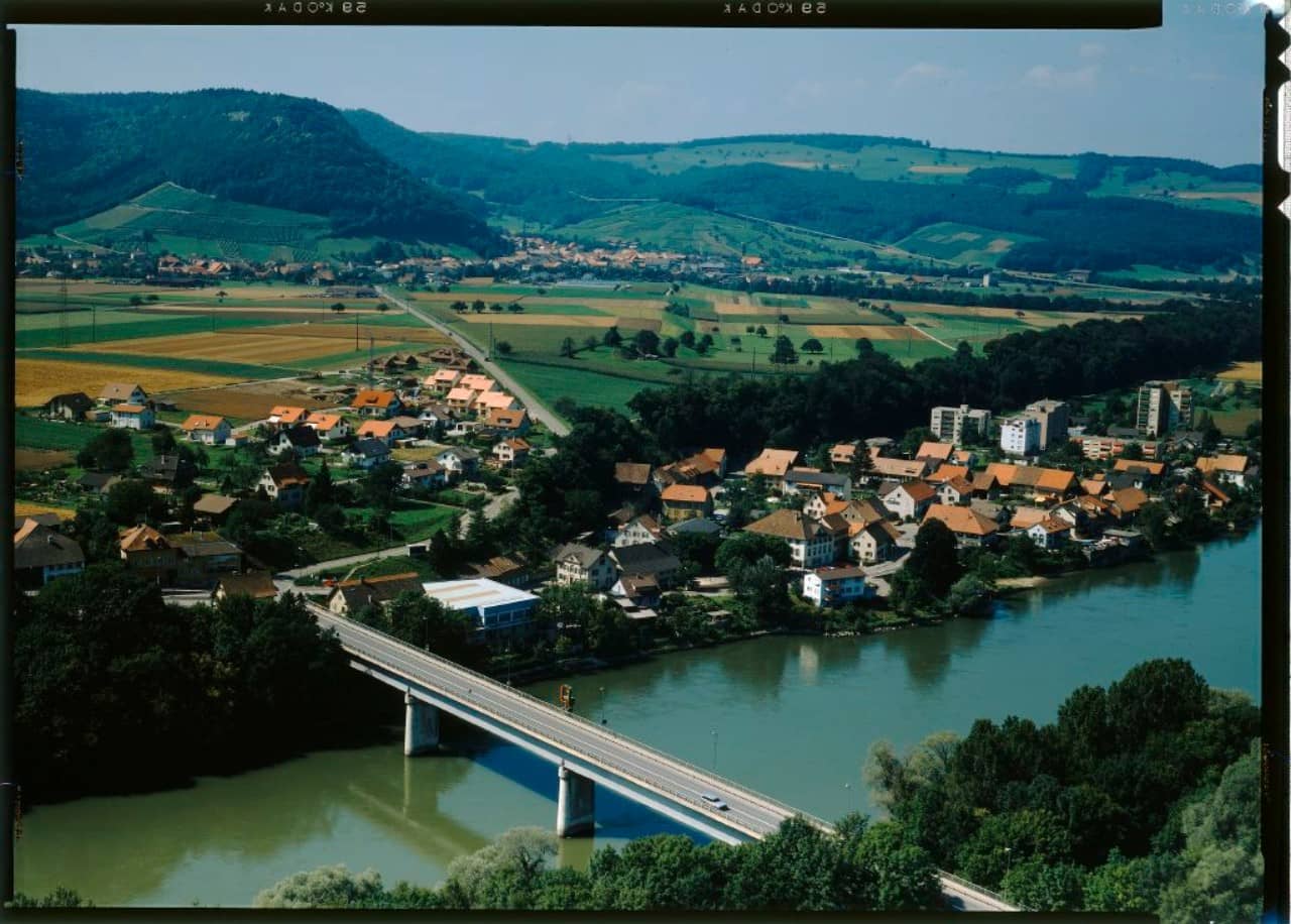 Aus der Vogelperspektive sieht man eine Brücke über die Aare spannen, die die Dörfer Stilli und Würenlingen miteinander verbindet. Das Foto ist in Farbe.