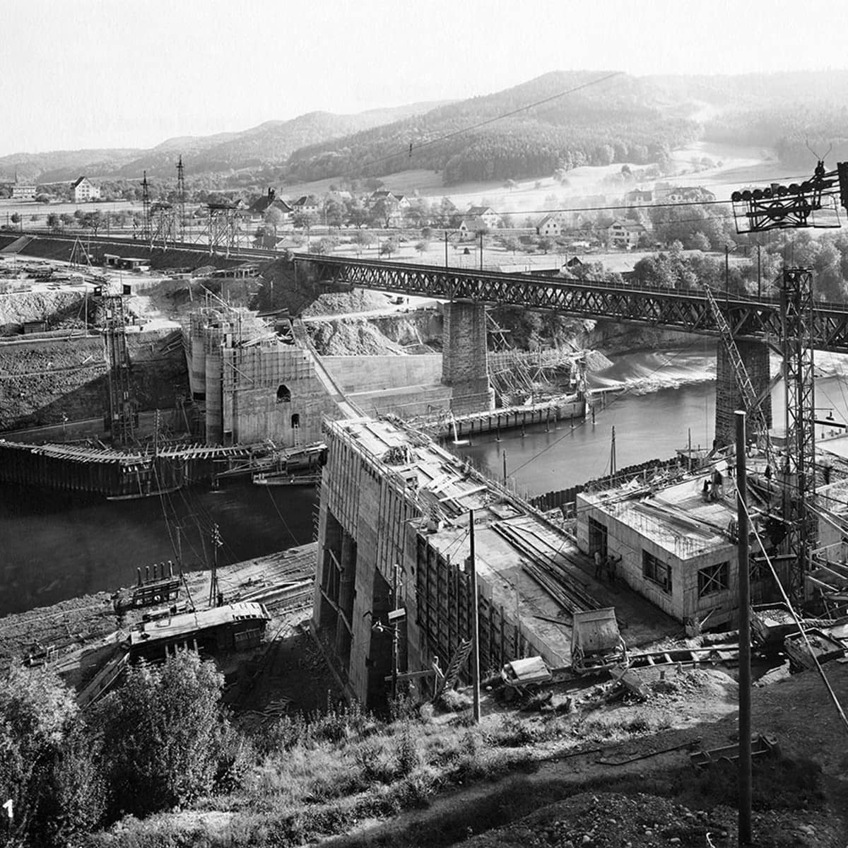 Die Schwarzweissfotografie stammt von 1931 und zeigt den Bau des ewz Wettingen. Noch ist die Betonkonstruktion über die Limmat noch nicht fertiggestellt.