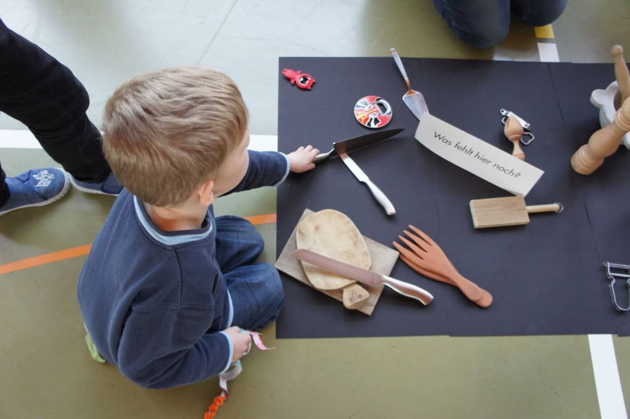 Schüler hockt am Boden mit Besteck und liest Zettel