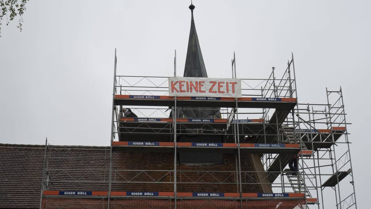 eine eingerüstete Kirche mit einem Banner auf dem "keine Zeit" steht