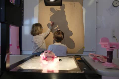 Kinder zeichnen eine Schattenfigur nach.
